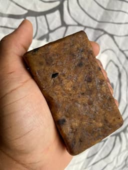 Vue de dessus d'un pain de Savon Noir Africain By Sibyllete tenu dans le creux de la main.