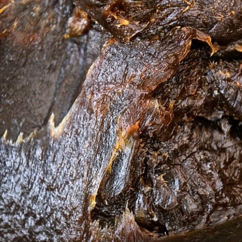 Gros plan sur la texture riche, visqueuse et artisanale du savon noir brut By Sibyllete.