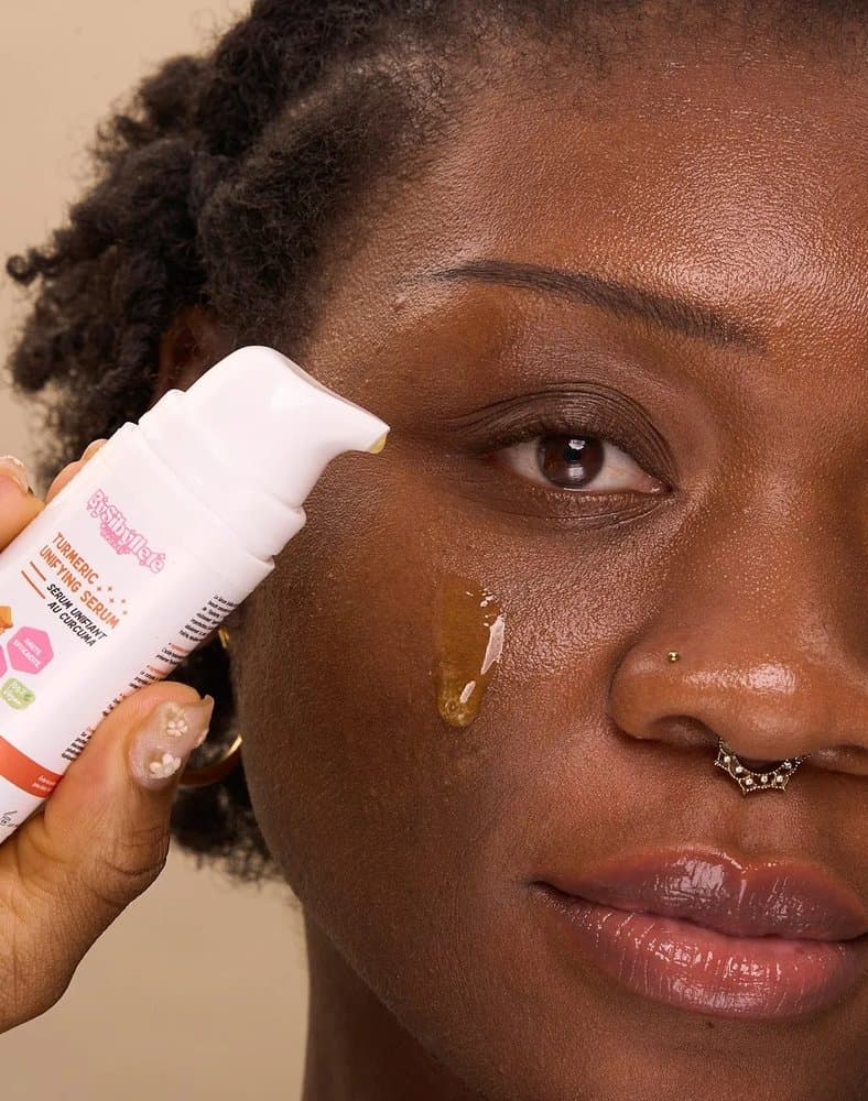Gros plan sur l'application d'une goutte de Sérum Unifiant au Curcuma By Sibyllete directement sur le visage pour révéler l'éclat du teint.